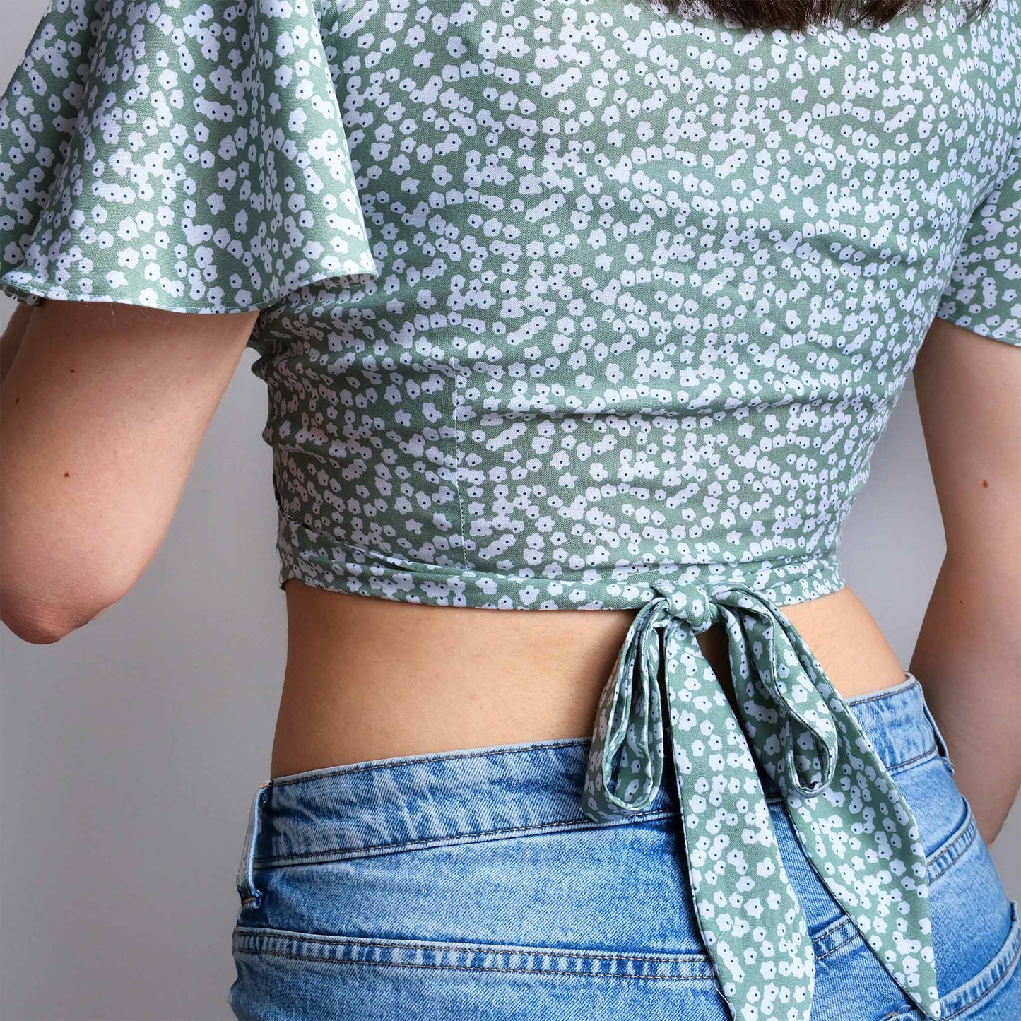 femme de dos portant un haut avec un joli nœud dans le dos et des manches évasées